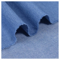 Un gros plan sur le Tissu jean 100 % coton au mètre, denim léger 4,5 oz bleu clair de Longan Craft France, met en évidence son tissage fin, sa texture lavée douce, ses plis délicats et son bord subtilement effiloché.