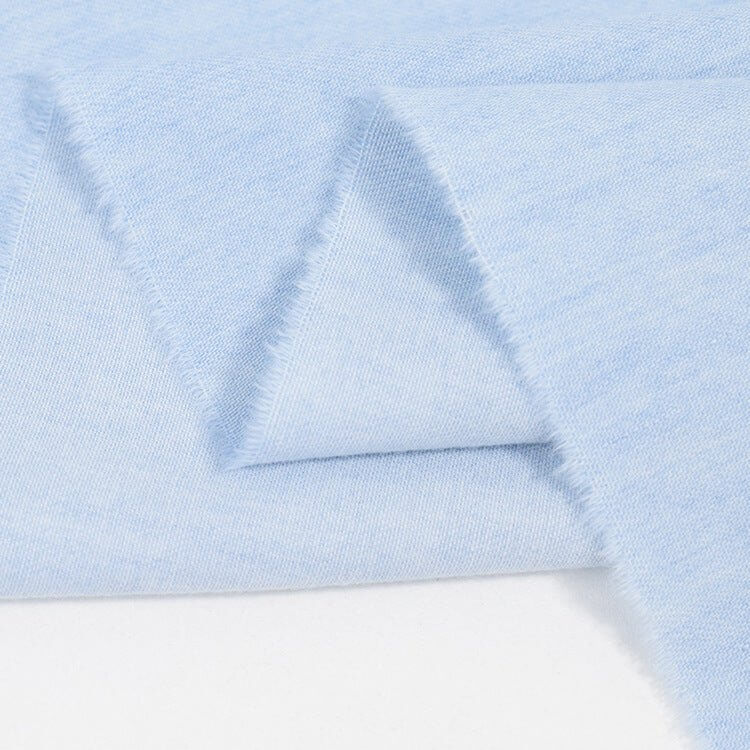 Gros plan sur le Tissu jean 100% coton au mètre de Longan Craft France : denim léger 4,5 oz bleu clair, à texture douce et légère avec bords légèrement effilochés.