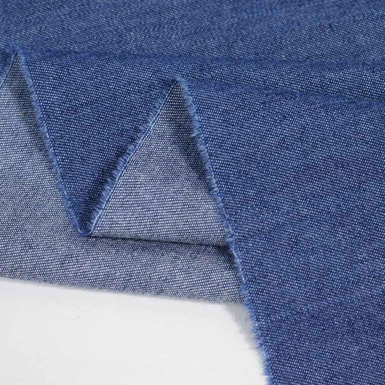 Gros plan sur deux pièces du Tissu jean 100 % coton au mètre (denim léger 4,5 oz bleu clair) de Longan Craft France, l'une étant superposée à l'autre et présentant une coupe en zigzag.