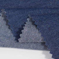Gros plan de trois pièces superposées de Tissu jean 100% coton au mètre (Denim léger 4,5 oz bleu clair, lavé) de Longan Craft France, avec des bords coupés en zigzag et des variations visibles de teinte et de texture sur un fond blanc.