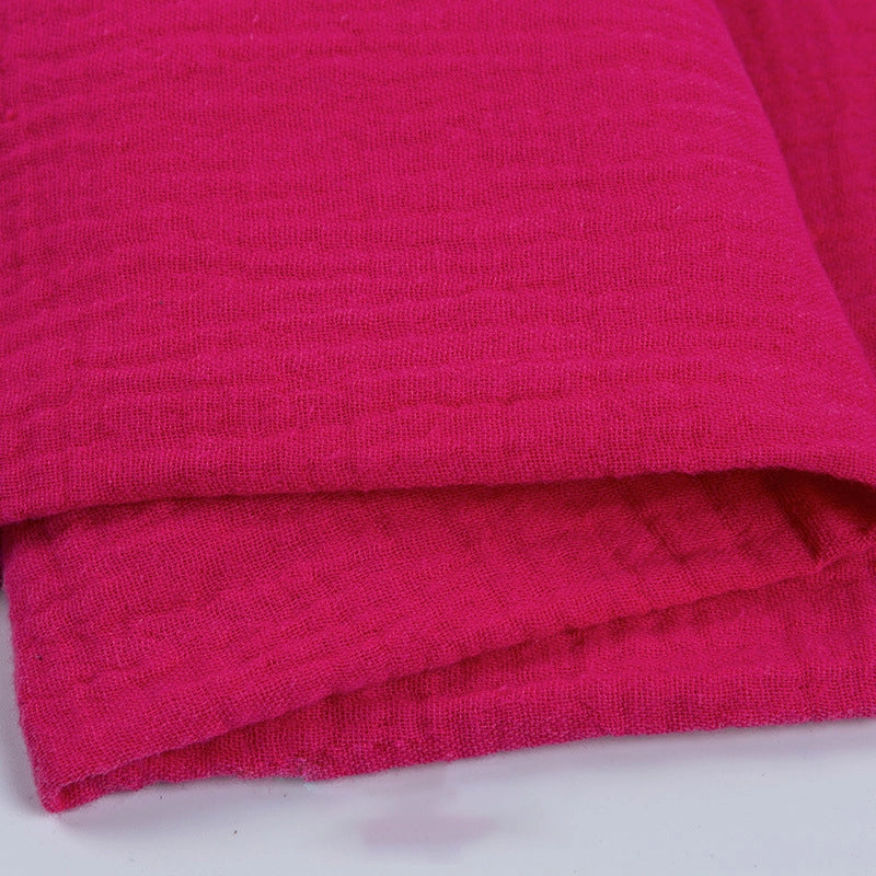 Gros plan sur deux pièces de Tissu double gaze 100 % coton au mètre rose vif de Longan Craft France, empilées pour mettre en valeur le tissage doux et léger et la surface texturée, parfaits pour les vêtements et les accessoires.