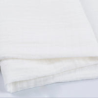 Gros plan sur le Tissu double gaze 100% coton de Longan Craft France, plié pour montrer sa surface douce et légèrement texturée. Ce tissu léger est parfait pour les vêtements et les accessoires.