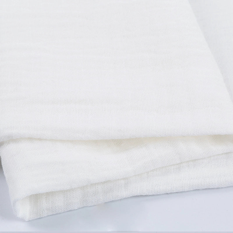 Gros plan sur le Tissu double gaze 100% coton de Longan Craft France, plié pour montrer sa surface douce et légèrement texturée. Ce tissu léger est parfait pour les vêtements et les accessoires.