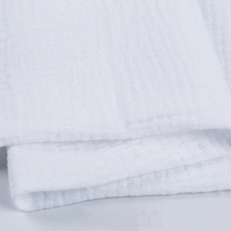 Gros plan sur le Tissu double gaze 100 % coton au mètre de Longan Craft France, un tissu blanc doux, léger et texturé, idéal pour les vêtements et les accessoires, soigneusement plié sur une surface légère.