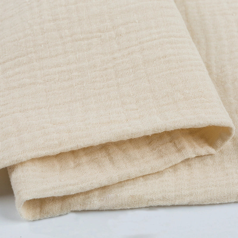 Gros plan sur le Tissu double gaze 100 % coton beige texturé de Longan Craft France, montrant son aspect léger, doux et légèrement froissé, idéal pour la confection de vêtements et d'accessoires.