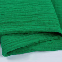 Gros plan sur deux couches de tissu texturé vert vif double gaze 100% coton de Longan Craft France, à l'aspect légèrement froissé. Léger et doux, il est parfait pour les vêtements et les accessoires.