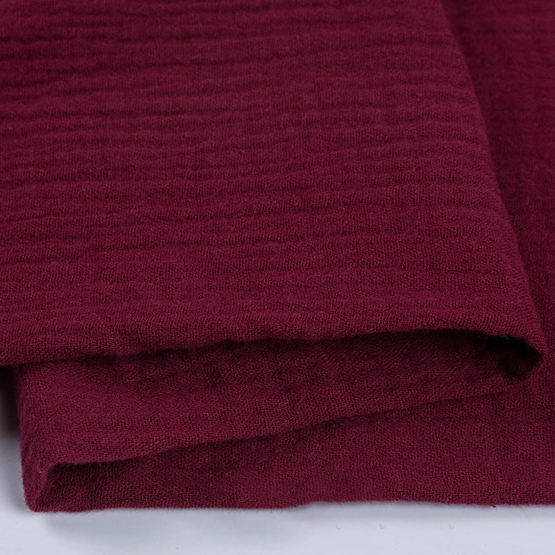 Gros plan sur le tissu double gaze 100 % coton au mètre de Longan Craft France, montrant sa couleur bordeaux profond, sa texture douce avec des stries horizontales - ce tissu léger et respirant est parfait pour les vêtements et les accessoires.