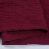 Gros plan sur le tissu double gaze 100 % coton au mètre de Longan Craft France, montrant sa couleur bordeaux profond, sa texture douce avec des stries horizontales - ce tissu léger et respirant est parfait pour les vêtements et les accessoires.