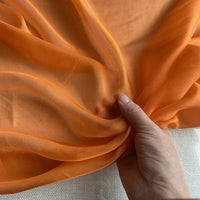 Une main présente la luxueuse, légère et transparente Mousseline de soie de mûrier de Longan Craft France - une mousseline de soie de mûrier naturelle vendue au mètre, parfaite pour les vêtements élégants.
