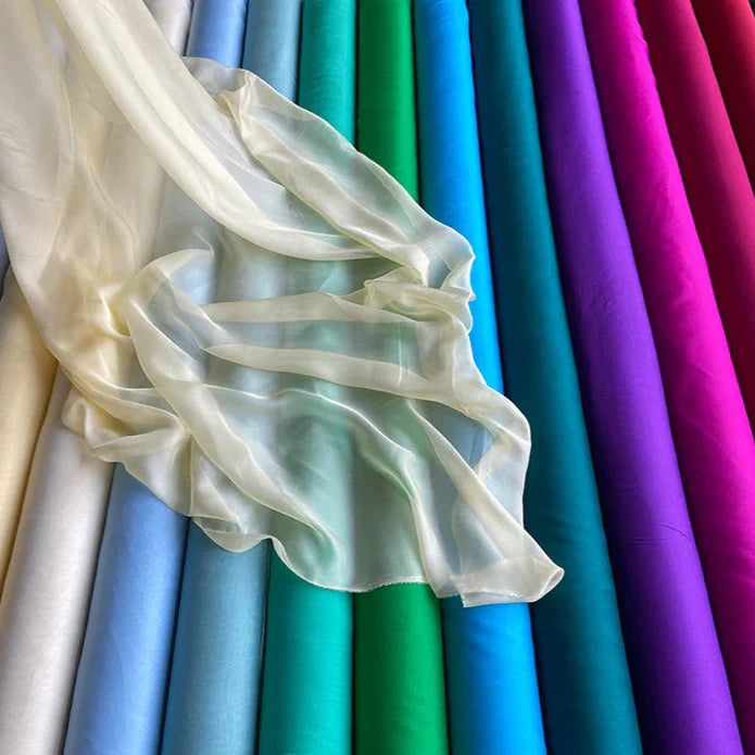 Une Mousseline de soie de mûrier de luxe de Longan Craft France est drapée sur des tissus de qualité supérieure bleus, verts, violets, roses et rouges - naturels, légers et purs pour l'habillement.