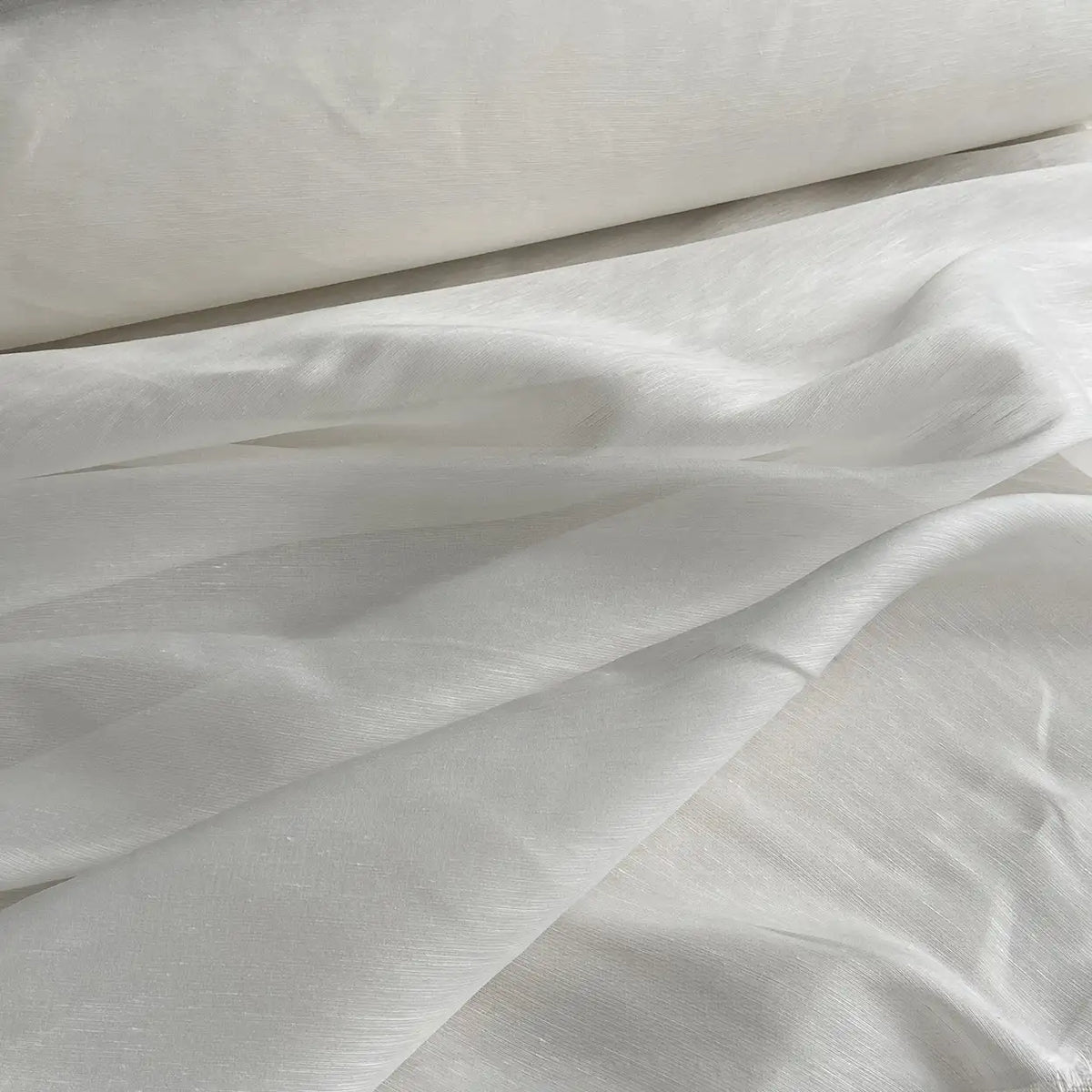 Un gros plan sur le Tissu soie et lin 14 mamans au mètre de Longan Craft France montre un organza de soie de mûrier lisse et subtilement brillant, doucement drapé et superposé, mettant en valeur sa légère translucidité - idéal pour des créations estivales pleines de vie.