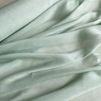 Le Tissu soie et lin 14 mamans au mètre de Longan Craft France est composé d'organza de soie de mûrier vert clair, drapé en plis aériens avec des ombres douces et une texture lisse et légèrement brillante - parfait pour les créations estivales.