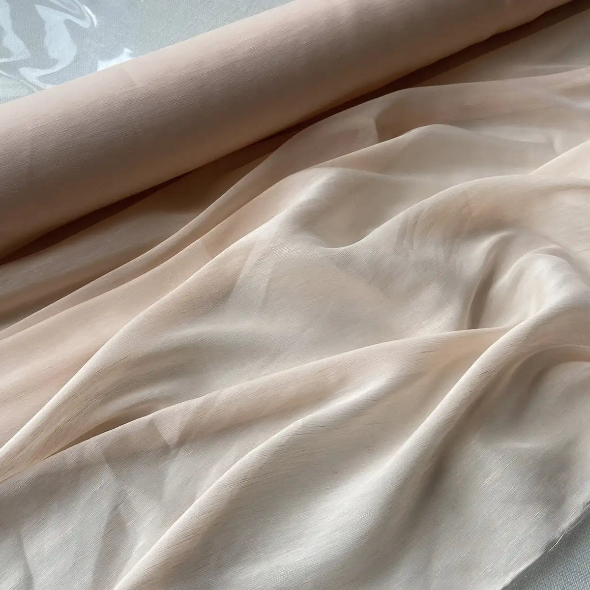 Un rouleau de Tissu soie et lin 14 mommes de Longan Craft France, organza de soie de mûrier aux couleurs vibrantes, déroulé pour montrer sa texture lisse et sa brillance - le tissu léger idéal pour l'été.