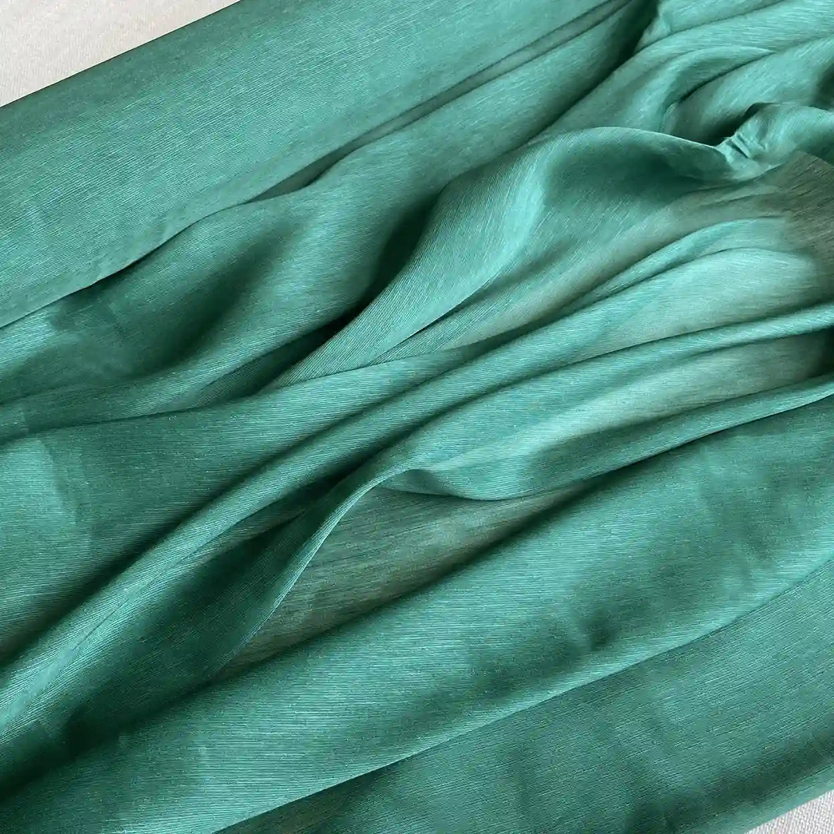Gros plan sur Tissu soie et lin 14 mamans au mètre de Longan Craft France : organza de soie de mûrier vert sarcelle, léger, à la texture douce et semi-transparente, luxueusement froncé en plis amples - idéal pour l'été.