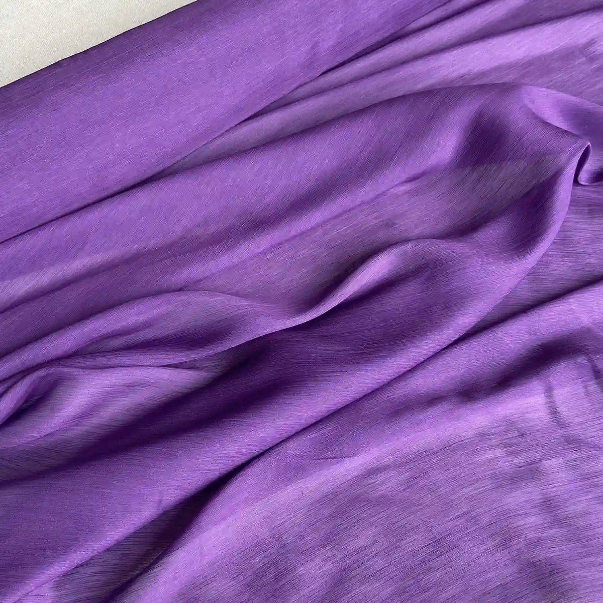 Un gros plan du Tissu soie et lin 14 mamans au mètre de Longan Craft France montre l'organza de soie de mûrier avec des plis naturels et une texture légèrement brillante et lisse - parfait pour l'été dans des couleurs vibrantes.