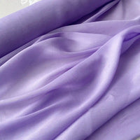 Tissu soie et lin 14 mommes au mètre de Longan Craft France, organza de mûrier aux couleurs vibrantes, est légèrement drapé et froncé pour révéler sa texture douce et fluide sous une lumière douce. Idéal pour l'été.