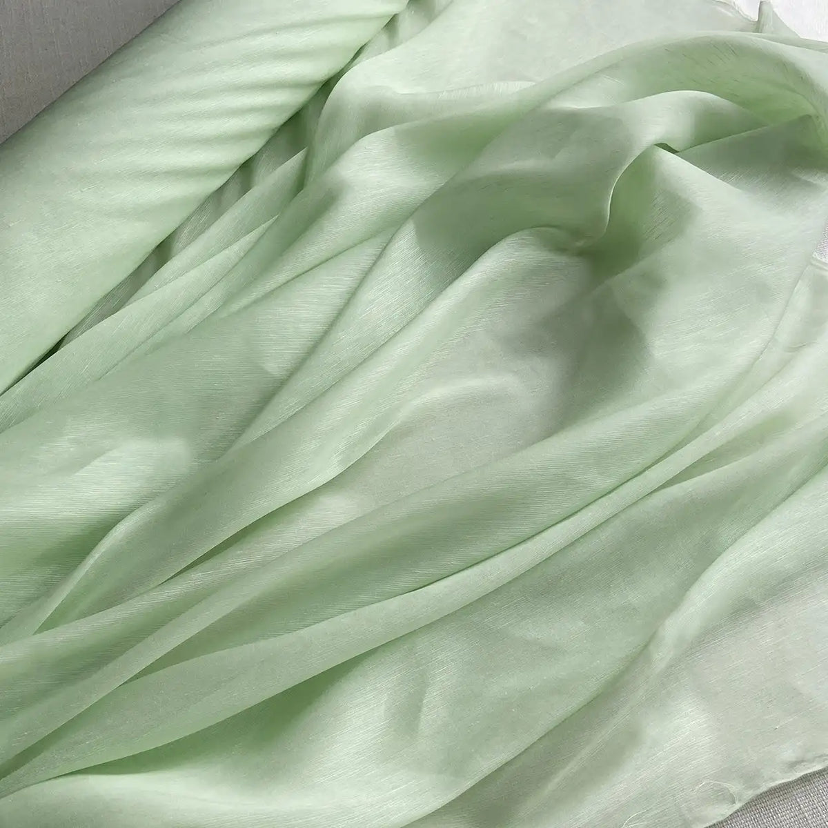 Un gros plan sur le Tissu soie et lin 14 mamans au mètre de Longan Craft France, un organza de soie de mûrier léger et brillant aux teintes vibrantes, révèle ses plis délicats et sa texture légèrement satinée, idéale pour l'été.