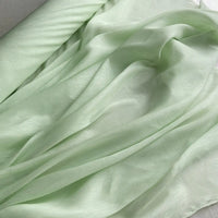 Un gros plan sur le Tissu soie et lin 14 mamans au mètre de Longan Craft France, un organza de soie de mûrier léger et brillant aux teintes vibrantes, révèle ses plis délicats et sa texture légèrement satinée, idéale pour l'été.