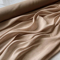 Gros plan sur Tissu soie et lin 14 mommes de Longan Craft France, un rouleau d'organza de soie de mûrier beige clair, partiellement déroulé avec des plis souples et des ombres douces, parfait pour les créations estivales.
