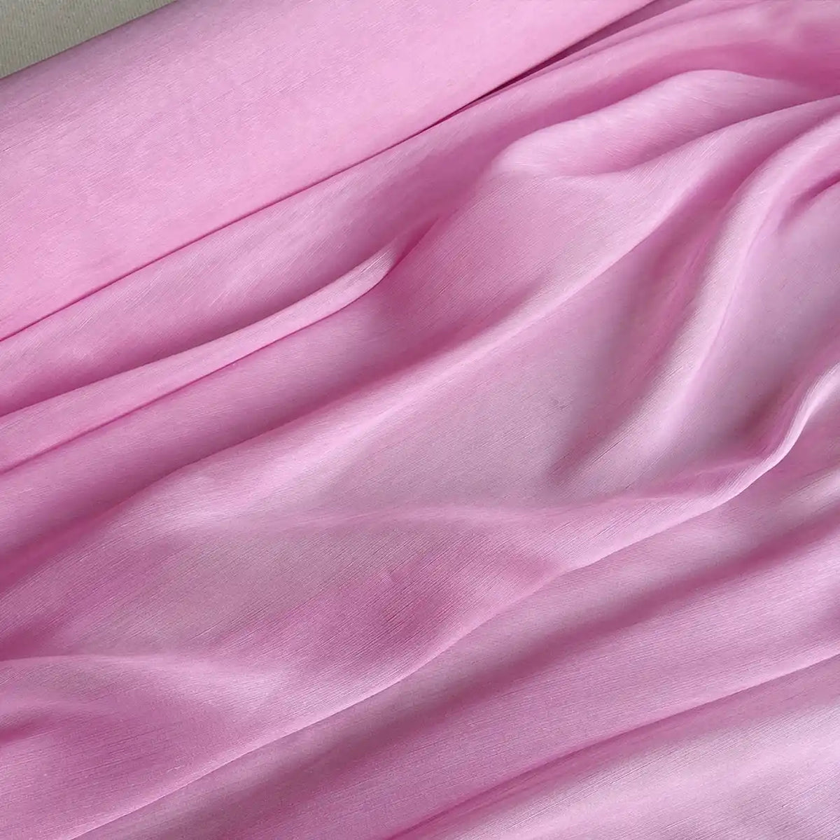 Gros plan sur le Tissu soie et lin 14 mamans au mètre de Longan Craft France en rose pâle, qui présente des plis doux et une texture organza lisse et légèrement transparente, parfaite pour les créations estivales de luxe.