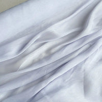 Un gros plan de Tissu soie et lin 14 mommes de Longan Craft France, d'un blanc doux et semi-transparent, montre des plis et des drapés doux, mettant en valeur la texture raffinée de l'organza de soie de mûrier - parfait pour les projets d'été.