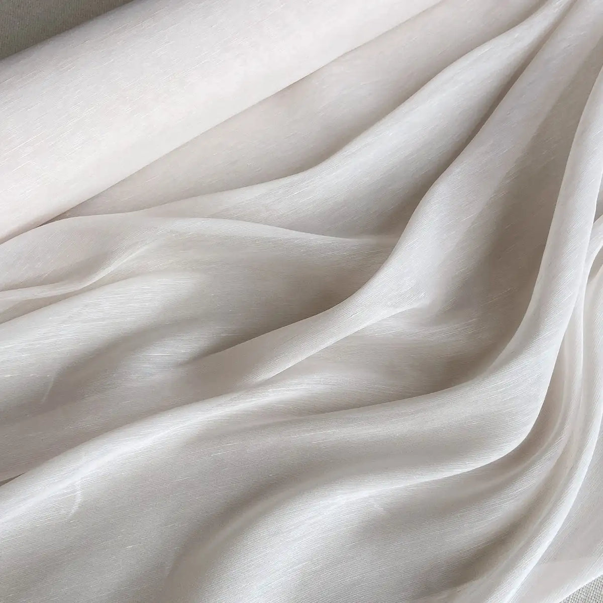 Un gros plan sur le Tissu soie et lin 14 mommes au mètre de Longan Craft France montre sa texture beige clair, lisse et semi-transparente, drapée en plis doux - un Organza de soie de mûrier doux, léger et idéal pour l'été.