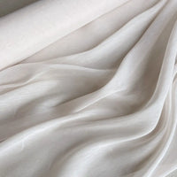 Un gros plan sur le Tissu soie et lin 14 mommes au mètre de Longan Craft France montre sa texture beige clair, lisse et semi-transparente, drapée en plis doux - un Organza de soie de mûrier doux, léger et idéal pour l'été.