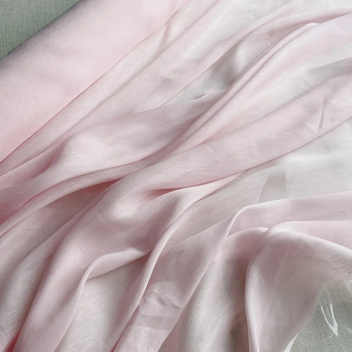 Gros plan sur le Tissu soie et lin 14 mamans au mètre de Longan Craft France - organza de soie de mûrier rose pâle - drapé en plis doux sur un fond neutre, un tissu soie-linen parfait pour l'été dans des couleurs vibrantes.