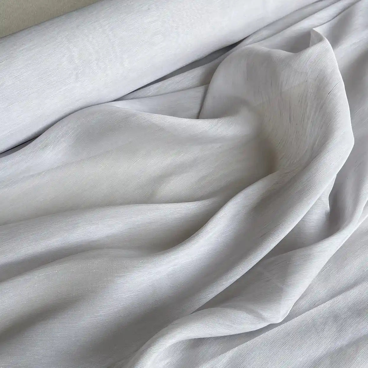 Gros plan sur le Tissu soie et lin 14 mommes au mètre-organza de soie de mûrier lumineuse, partiellement déroulé, à la texture lisse idéale pour des créations estivales élégantes et raffinées de Longan Craft France.
