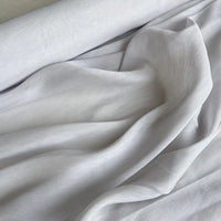 Gros plan sur le Tissu soie et lin 14 mommes au mètre-organza de soie de mûrier lumineuse, partiellement déroulé, à la texture lisse idéale pour des créations estivales élégantes et raffinées de Longan Craft France.