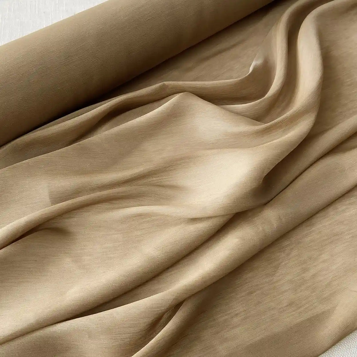 Un rouleau de Tissu soie et lin 14 mommes de Longan Craft France, partiellement déroulé sur une surface plane, présente des plis doux et l'élégance de ce luxueux organza de soie de mûrier vibrant, idéal pour l'été.