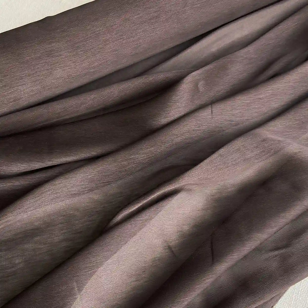 Gros plan sur Tissu soie et lin 14 mamans au mètre de Longan Craft France, qui présente un organza de soie de mûrier gris brunâtre aux plis visibles, à la texture naturelle et aux reflets lumineux - le luxe léger idéal pour l'été.