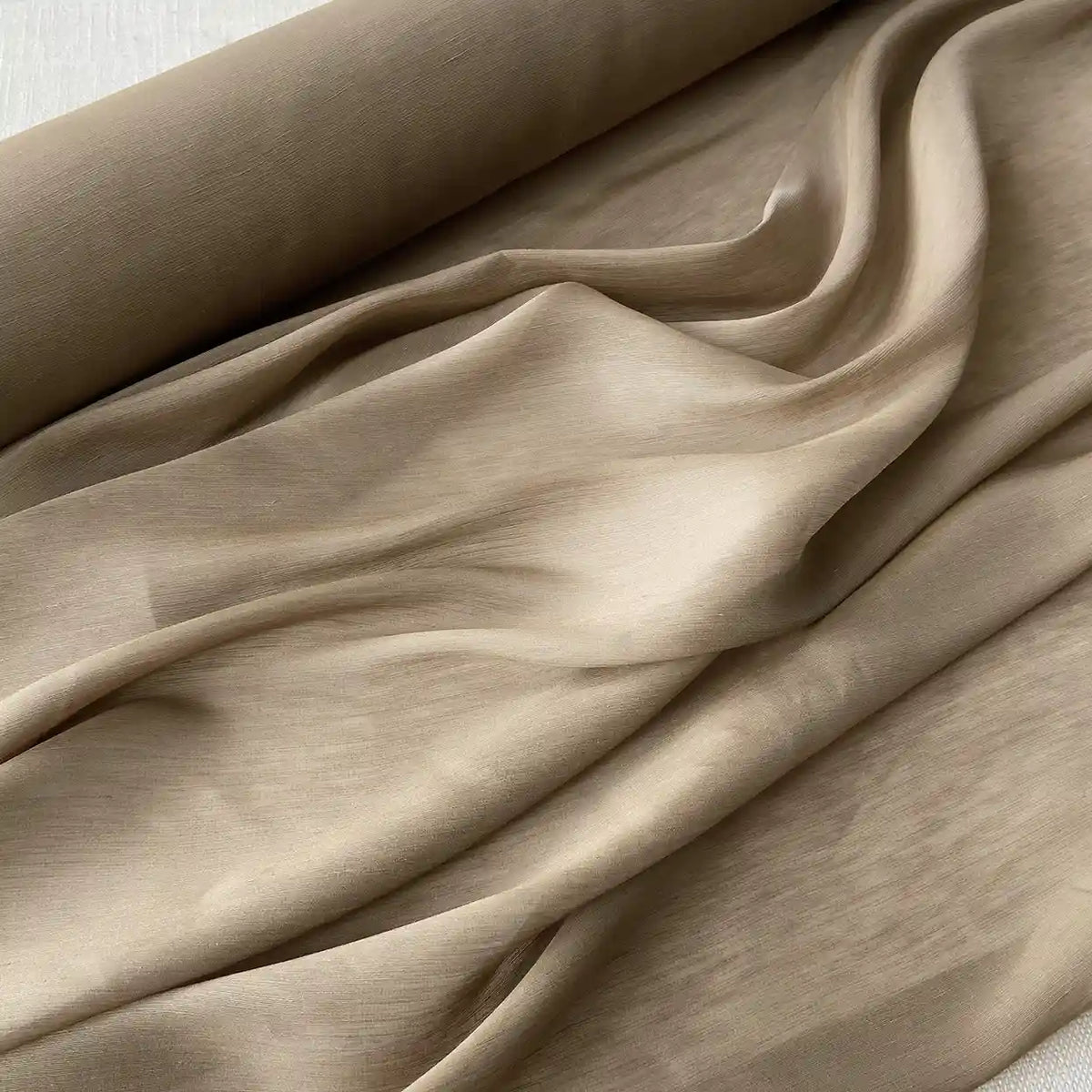 Un gros plan du Tissu soie et lin 14 mamans au mètre de Longan Craft France montre cet organza de soie de mûrier drapé en plis souples, mettant en valeur sa texture lisse et son éclat vibrant - une soie parfaite pour l'été.