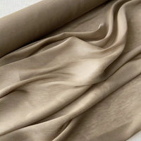 Un gros plan du Tissu soie et lin 14 mamans au mètre de Longan Craft France montre cet organza de soie de mûrier drapé en plis souples, mettant en valeur sa texture lisse et son éclat vibrant - une soie parfaite pour l'été.