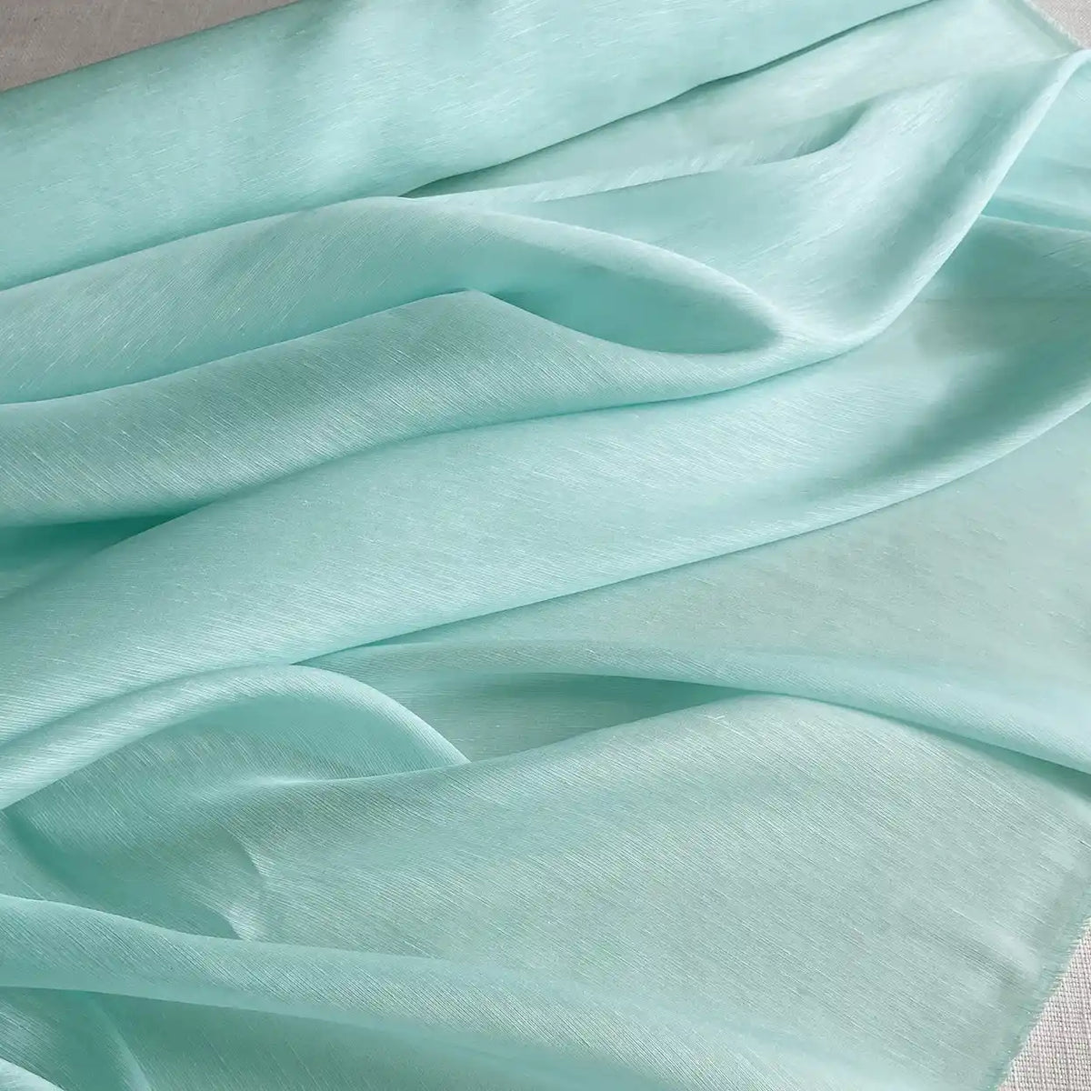 Gros plan sur le Tissu soie et lin 14 mommes de Longan Craft France - un organza de soie de mûrier aux couleurs vibrantes, drapé et plié en couches douces et fluides sur une surface plane.