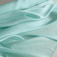 Gros plan sur le Tissu soie et lin 14 mommes de Longan Craft France - un organza de soie de mûrier aux couleurs vibrantes, drapé et plié en couches douces et fluides sur une surface plane.