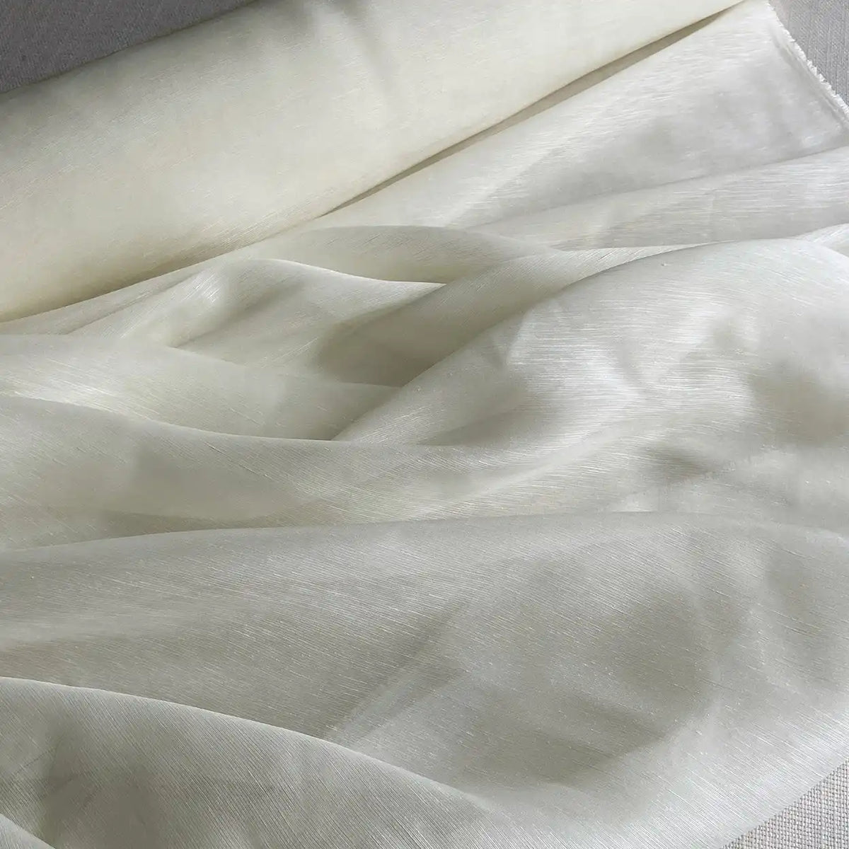 Gros plan sur un rouleau de Longan Craft France Tissu soie et lin 14 mommes au mètre Organza de soie de mûrier, transparent et léger avec une texture douce et légèrement brillante, drapé en plis doux - idéal pour l'été.