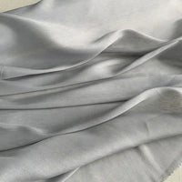 Un gros plan du Tissu soie et lin 14 mamans au mètre de Longan Craft France montre des plis délicats et une brillance subtile, soulignant le drapé élégant et la texture de cet organza de ver à soie luxueux et vibrant, idéal pour l'été.