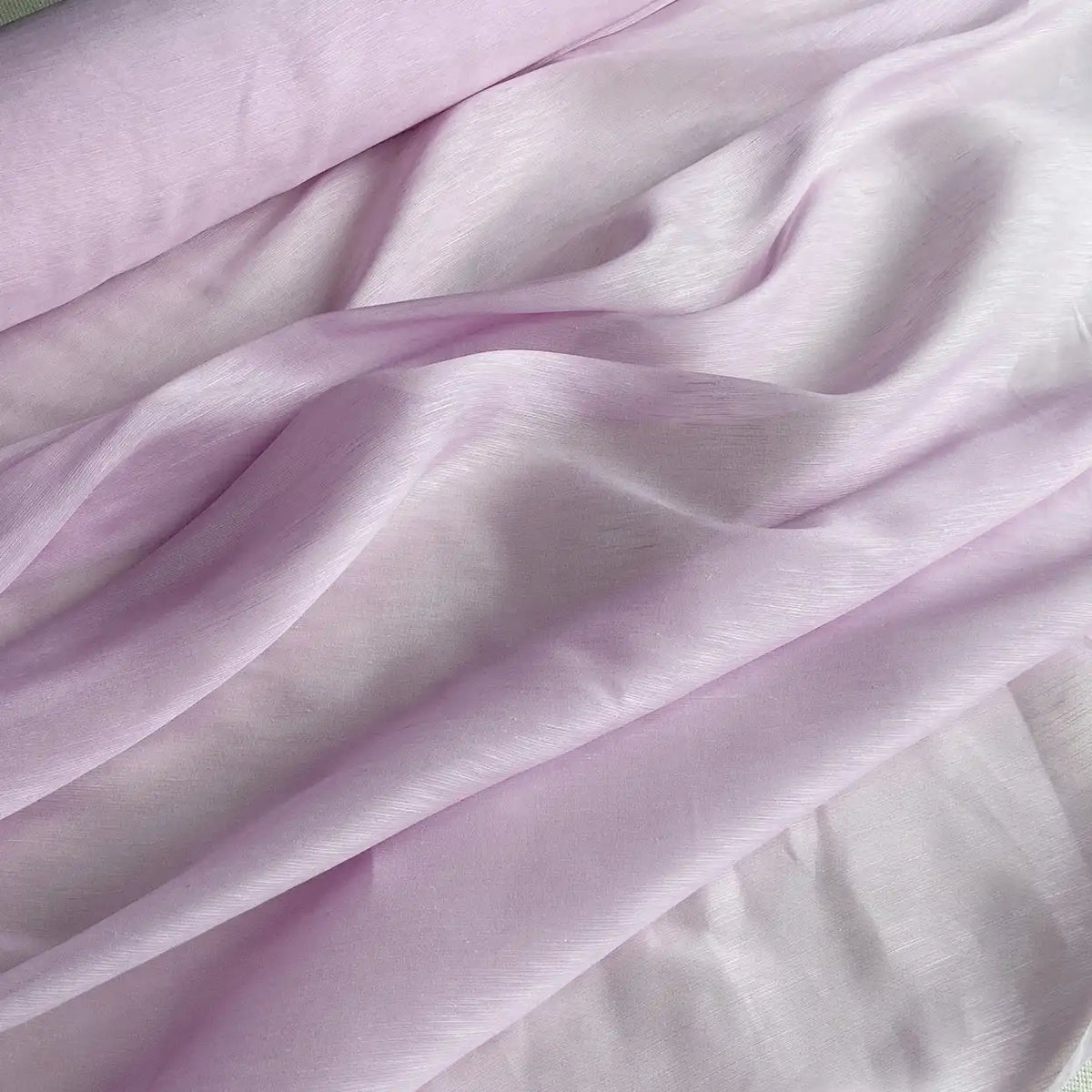 Le Tissu soie et lin 14 mommes de Longan Craft France est un organza de soie-linen rose pâle, semi-transparent, drapé pour mettre en valeur sa texture lisse et sa brillance douce - un tissu idéal pour l'été, disponible au mètre dans des couleurs vibrantes.