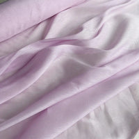 Le Tissu soie et lin 14 mommes de Longan Craft France est un organza de soie-linen rose pâle, semi-transparent, drapé pour mettre en valeur sa texture lisse et sa brillance douce - un tissu idéal pour l'été, disponible au mètre dans des couleurs vibrantes.