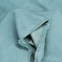 Gros plan sur Longan Craft France Microsuède polyester multicolore au mètre, montrant sa texture brossée en peau de pêche bleu clair, son toucher doux et son bord plié non fini et légèrement effiloché, idéal pour la confection de vêtements.