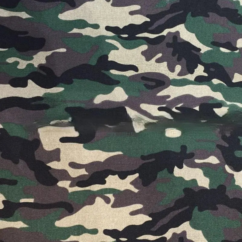 Ce tissu imprimé camouflage au mètre de Longan Craft France présente des tons verts, bruns et noirs avec une déchirure horizontale et des bords effilochés au milieu - parfait pour les projets de vêtements ou de bagages.