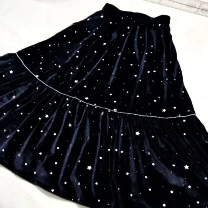 La Jupe midi plissée femme de Longan Craft France, présentée à plat sur une surface légère, présente un motif en velours noir à étages, parsemé de petites étoiles blanches. Patron de couture PDF gratuit à télécharger.