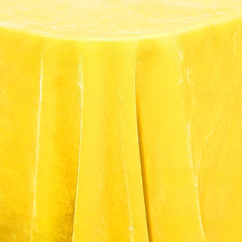 Un gros plan d'une table ronde drapée de Velours de soie de mûrier doux de Longan Craft France montre le tissu d'ameublement lisse en soie-rayon et ses élégants plis verticaux tombant en cascade sur les côtés.