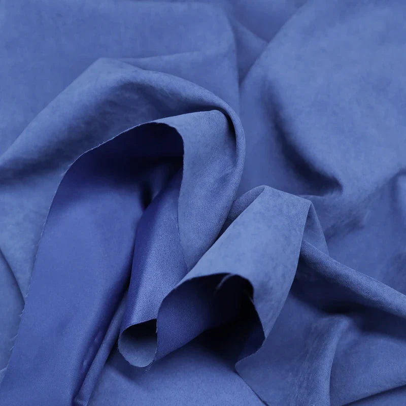 Gros plan sur le microsuède polyester multicolore au mètre de Longan Craft France, tissu peau de pêche brossée doux et agréable, parfait pour la confection de vêtements, drapé et plié pour révéler sa texture lisse et ses plis délicats.