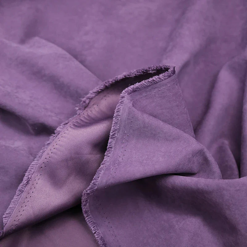 Gros plan sur Microsuède polyester multicolore au mètre de Longan Craft France, un doux tissu peau de pêche brossée avec texture visible et bords effilochés, parfait pour la confection de vêtements et la décoration.