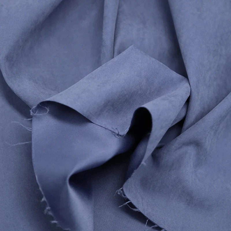 Gros plan sur le polyester microsuède multicolore, doux et froissé, aux reflets subtils et aux bords effilochés. Le tissu peau de pêche brossée de Longan Craft France, parfait au mètre pour vêtements et décoration.