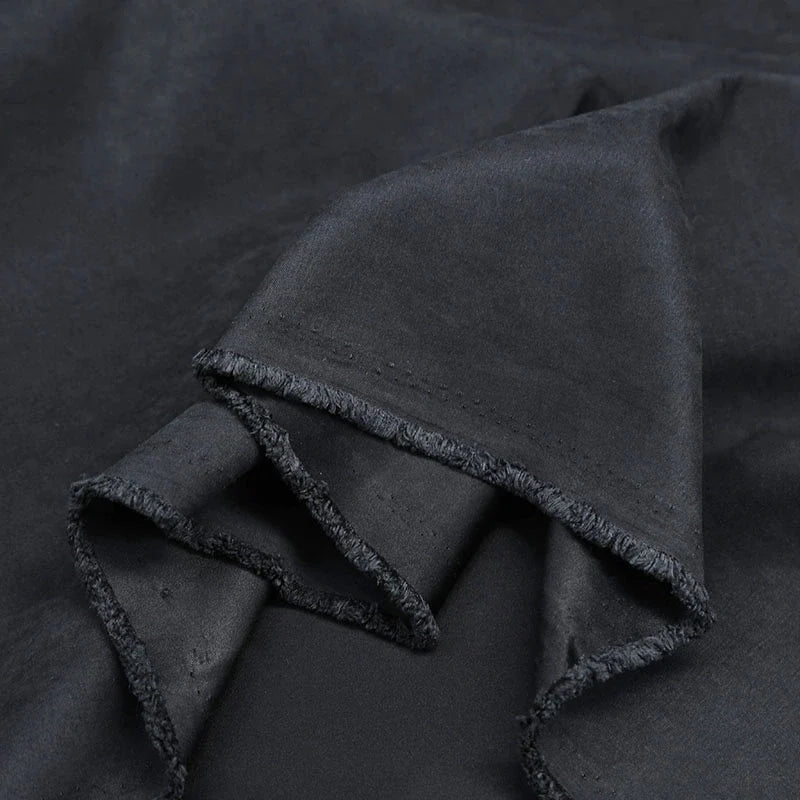 Gros plan sur Microsuède polyester multicolore au mètre de Longan Craft France, qui présente une texture brossée peau de pêche avec des bords bruts et des plis subtils. Ce tissu doux et légèrement brillant est parfait pour les vêtements et la décoration.