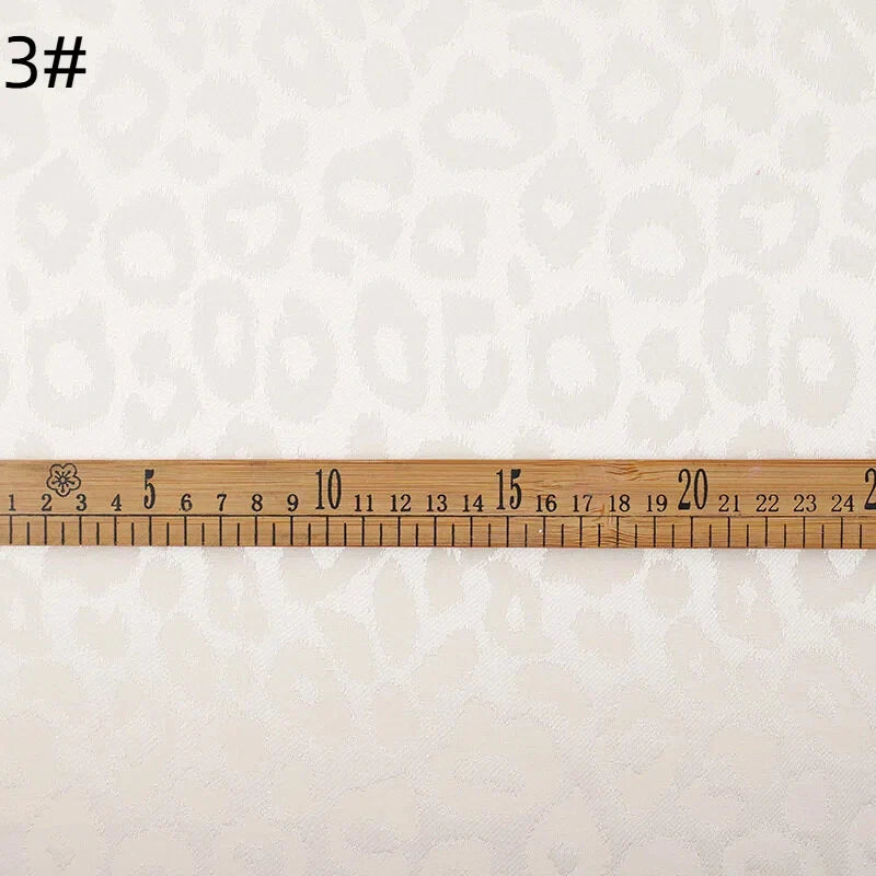 Une règle en bois de 25 cm est posée sur le Tissu satin jacquard léopard au mètre de Longan Craft France, un tissu jacquard multicolore destiné aux chemises de bricolage ; le chiffre "3#" apparaît dans le coin supérieur gauche.