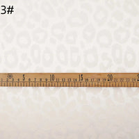 Une règle en bois de 25 cm est posée sur le Tissu satin jacquard léopard au mètre de Longan Craft France, un tissu jacquard multicolore destiné aux chemises de bricolage ; le chiffre "3#" apparaît dans le coin supérieur gauche.